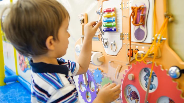 Enfant jouant avec son tableau d'activité Montessori