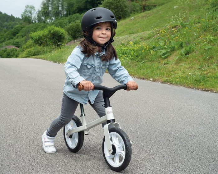 Une petite fille équipée d'un casque sur sa draisienne