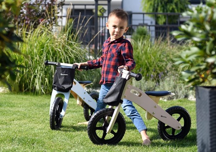 Un petit garçon se tenant debout entre deux draisiennes évolutives dans un jardin