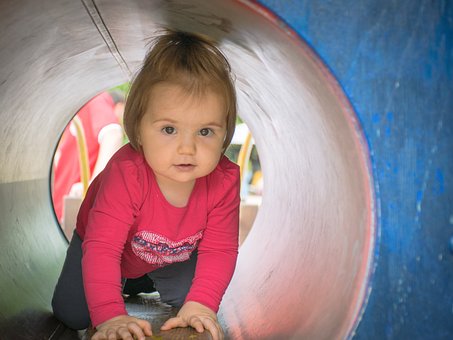 Une petite fille dans un tunnel de parcours de motricité.