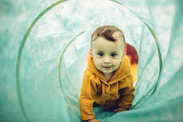 Bébé fille rampant dans un tunnel de jeu pour un parcours d'exercice de motricité