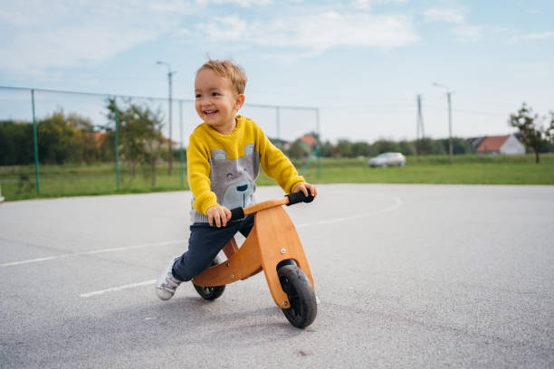 Un jeune garçon jouant sur une draisienne en bois sur un terrain de sport.