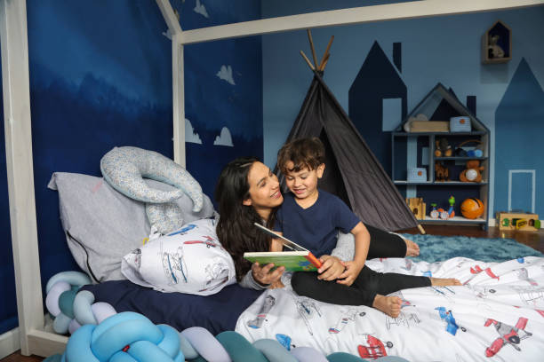 Dans une chambre équipée d'un lit de type Montessori, une mère fait la lecture à son fils de quatre ans.