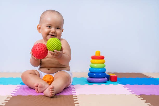 A toddler plays with rubber balls to develop hand motor skills Un jeune enfant joue avec des balles en caoutchouc pour développer la motricité de ses mains.