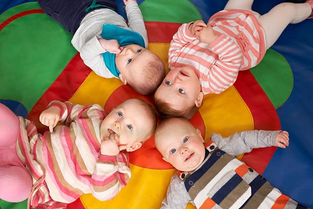 Playing with friends 4 bébés allongés sur un tapis de motricité