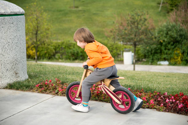 Sur le trottoir, le petit garçon joue avec sa draisienne