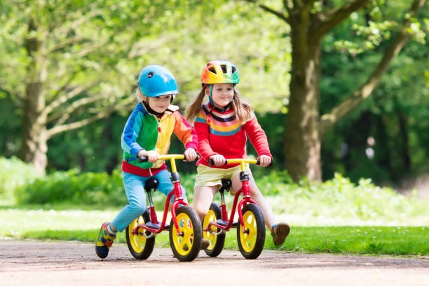 Enfants faisant du vélo d'équilibre : la draisienne, dans un parc ensoleillé
