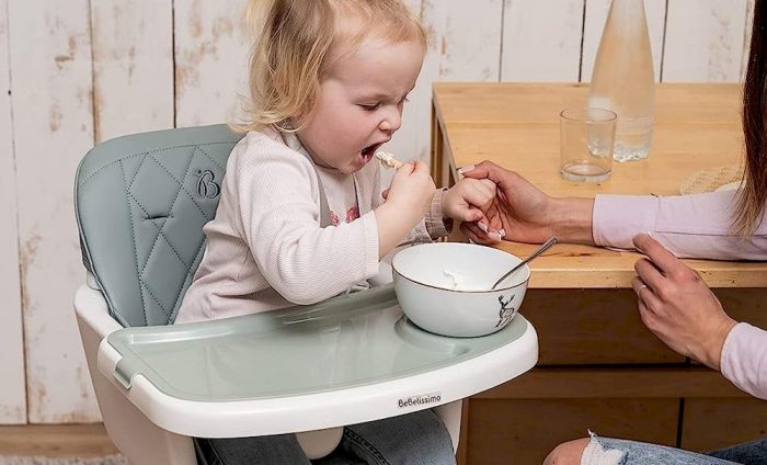 Une mère nourrissant son enfant assise sur une Chaise haute évolutive