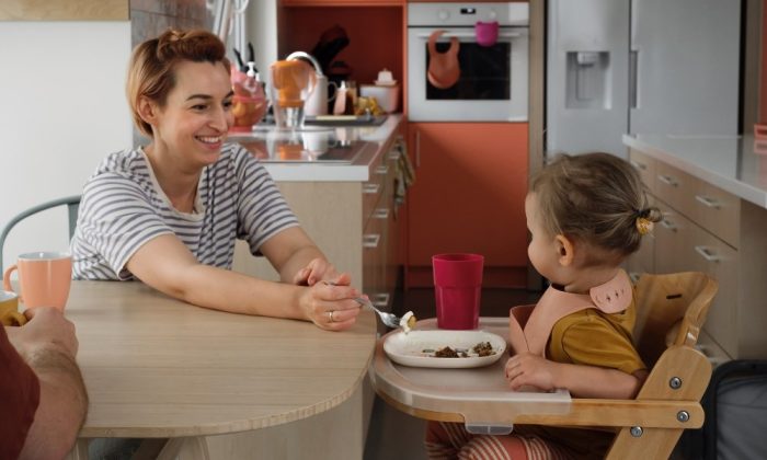 Une mère nourrissant son enfant assise sur une Chaise haute évolutive