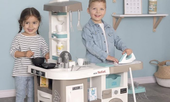 Un enfant préparant à manger avec la cuisine Smoby et un autre enfant repassant une linge