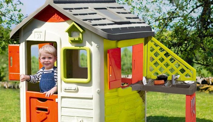 Un enfant à l'intérieur d'une maisonnette avec une cuisine Smoby