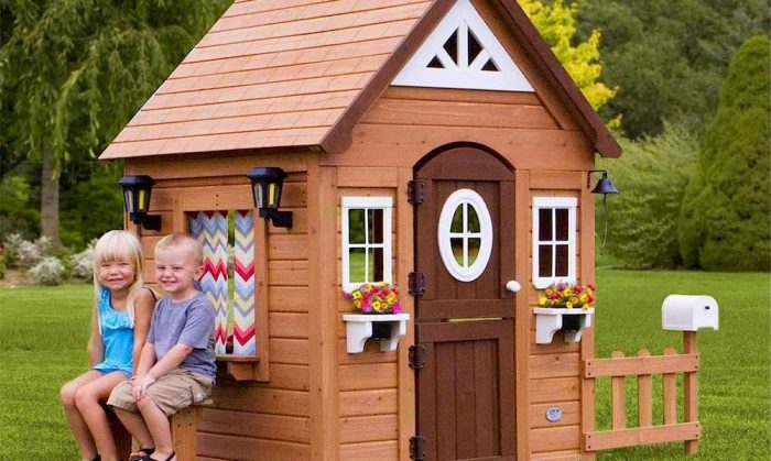 Deux enfants assises à l'extérieur d'une maisonnette en bois
