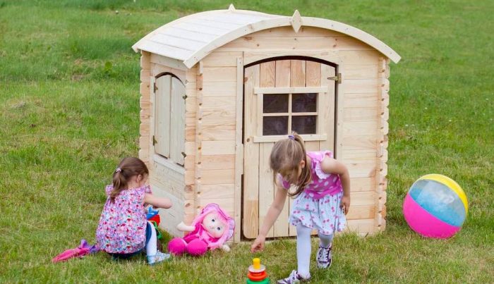 Deux enfants jouant près d'une maisonnette en bois