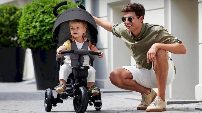 Père avec son enfant assise sur un tricycle Kinderkraft
