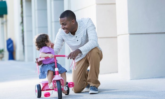 Un père avec sa fille assise sur un tricycle évolutif